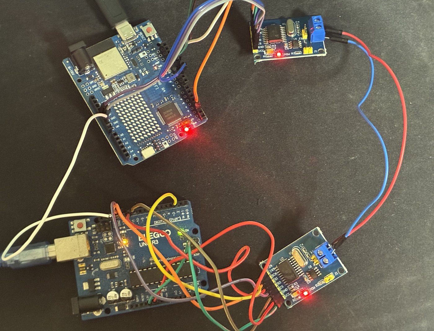 実際に組んだところ。上がUno R4、下がUno R3で、それぞれにMCP2515モジュールをつなぎ、2枚のネジ端子台の間を赤と青の線で、2台のArduinoのGNDピンどうしを白い線で結んでいる